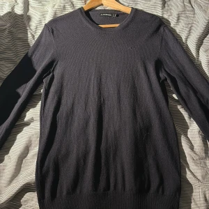 Svart stickad tröja från J.Lindeberg - Svart stickad tröja från J.Lindeberg i storlek XL. Tröjan har rund hals, diskret broderad logga på bröstet och ribbade muddar vid ärmslut och nederkant. Perfekt för dig som gillar stilrena och klassiska plagg med snygg passform. Har dock tyvärr krympt i tvätten och passar nu M/L. Pris kan diskuteras vid snabb affär.