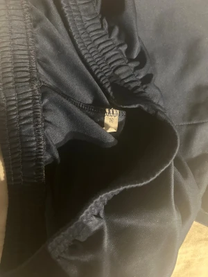 Mörkblå Nike shorts strl 16 - Säljer ett par mörkblå sportiga shorts från Nike med elastisk midja och klassisk vit swoosh-logga på benet. Perfekta för träning eller chill dagar. Lätta och bekväma med enkel design.