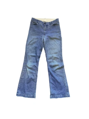 Blå bootcut jeans med lagningar - Snygga blå jeans med bootcut passform och klassisk femficksdesign. Jeansen har lagningar på insidan och nära bakfickorna! Tillverkade i slitstarkt denimtyg med normal midja och dragkedja framtill.