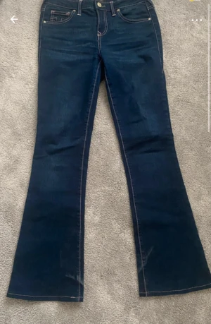 True Religion blå bootcut jeans - Snygga mörkblå jeans från True Religion med bootcut. Jeansen har kontrastsömmar . Storlek 26 och modellen Becca.