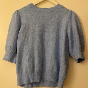 Ljusblå stickad tröja Vero Moda - Superfin ljusblå stickad tröja från Vero Moda med puffade korta ärmar och ribbade muddar vid hals, ärmslut och nederkant. Mjuk och skön, perfekt för dig som gillar en chill och trendig look. Passar dig som vill ha något enkelt men ändå snyggt.