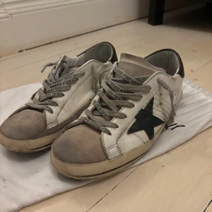 Golden Goose vita sneakers med stjärna - Halloj. Jag säljer nu mina riktigt feta goolden goose som jag haft i runt ett halvår. Dom är köpta ifrån merch Sweden för 4500kr. Dom är i rätt så gott skick men de finns några slitningar och som ni ser på 3 bilden så är sulan trasig men provisionallt limmad. Hör gjärna av er☺️