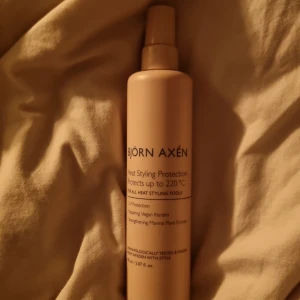 Björn Axén Heat Styling Protection - Värmeskyddsspray från Björn Axén i beige plastflaska med spraymunstycke. Skyddar håret vid styling upp till 220°C och innehåller vegansk keratin samt marina växtextrakt. Ger UV-skydd och passar alla värmestylingverktyg.
