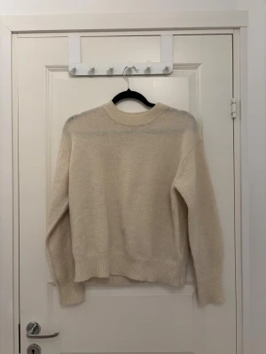 Beige stickad tröja från Gina Tricot - Mysig beige stickad tröja från Gina Tricot med rund hals och ribbade muddar vid ärmslut och nederkant. Perfekt för dig som gillar enkel och clean stil. Passar dig som vill ha en klassisk och skön tröja till hösten och vintern.