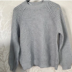 Ljusgrå stickad tröja med struktur - Snygg ljusgrå stickad tröja med grov struktur och rund hals. Tröjan har långärmade raglanärmar och ribbade muddar vid hals, ärmslut och nederkant. Perfekt för dig som gillar en chill och enkel stil. Lånade bilder! Den är lite urtvättad men superfin, därav priset!❤️ i storlek S