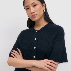 Mörkblå stickad kofta från Gina tricot - Kortärmad, mörkblå stickad kofta från Arket med rund hals och kontrasterande vita knappar framtill. Mjuk och fluffig känsla, perfekt för lager-på-lager. Enkel och stilren design som funkar till många olika looks. Använd 1 gång