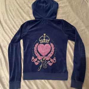 Juicy Couture tröja - blå hoodie från Juicy Couture med unikt tryck på baksidan. Står att den är i storlek XL men skulle säga att den snarare är en S då den sitter tajt på mig som vanligtvis har S. Syns att den är använd men fortfarande i bra skick.