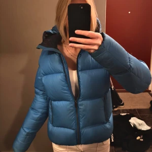Blå Colmar pufferjacka med huva - Säljer en blå pufferjacka från Colmar! Jackan har en klassisk pufferlook och Colmar-logga på ärmen. Perfekt för kalla dagar och riktigt snygg, helt nytt skick!☺️