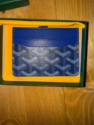 Korthållare  - En marinblå plånbok är den perfekta kombinationen av tidlös elegans och diskret lyx. Med sitt ikoniska handmålade mönster och djupa blå nyans ger den ett exklusivt uttryck som passar både vardag och fest. Plånboken är lätt, hållbar och designad med smarta fack som gör det enkelt att organisera kort och kontanter. Ett stilfullt statement för dig som vill bära med dig lyx i varje detalj.