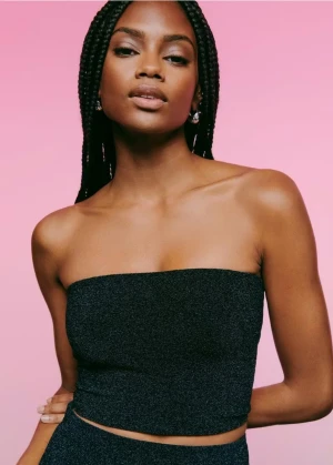 Svart glittrig tubtop stl xs Gina Tricot  - Snygg svart tubtop med glittrig yta som ger en elegant touch. Perfekt för att lyfta din outfit med lite extra glamour. Passar bra till både vardag och speciella tillfällen. Använd en gång