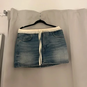 Blå jeanskjol med vit snörning - Snygg blå jeanskjol med vit, elastisk midja och snörning framtill. Kjolen har klassiska fickor både fram och bak. Väldigt unik och säljs ej mer. Köpt på Zara i bali. Aldrig använd!  Passar 36/38 