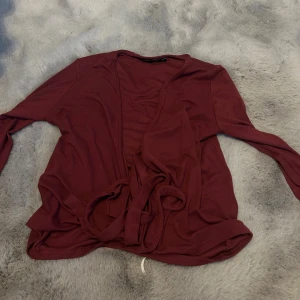 Vinröd omlottkofta med knytband - Snygg vinröd omlottkofta med långa ärmar och knytband i midjan. Perfekt för lager-på-lager och ger en chill vibe till din outfit. Mjuk och skön, passar dig som gillar enkel stil med lite extra detalj.