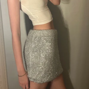 Glittrig silver minikjol/topp - Glittrig kjol som även går att styla som topp. Kolla sista bilden. Perfekt till jul och ny år. Jag har vikt in den för att få den lite kortare. 