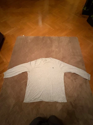 Ljusgrå långärmad tröja från Polo Ralph Lauren - Bra julklapp!!!Snygg ljusgrå långärmad tröja från Polo Ralph Lauren med klassisk rund hals och den ikoniska lilla broderade loggan på bröstet. Tillverkad i mjuk bomull som är skön mot huden och har en normal passform. Perfekt för chill dagar eller när du vill ha en clean look.(🔥om det syns några fleckar så är det sånt som går att tvätta 🧽 🔥)