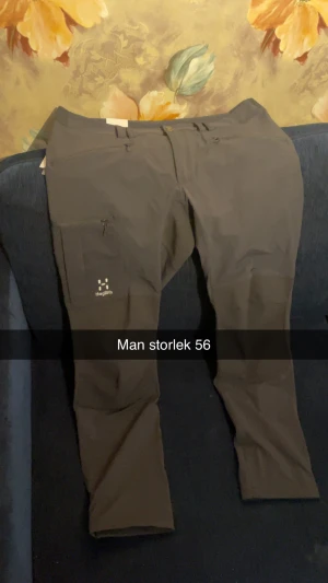 Svarta friluftsbyxor från Haglöfs - Svarta friluftsbyxor från Haglöfs med dragkedjeficka på benet och diskret logga. Byxorna har en modern passform och är tillverkade i ett slitstarkt syntetmaterial som passar perfekt för utomhusaktiviteter. Med prislapp 