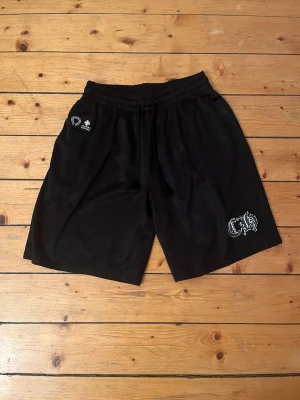 Svarta mesh shorts från Chrome Hearts - Svarta mesh shorts från Chrome Hearts. De har elastisk midja med snörning för skön passform och är tillverkade i luftig polyester. Perfekta för chill eller sportiga dagar, loose fit och stilren design.