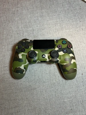 Ps4 kontroll Camouflage Edition - Snygg Sony DualShock 4 trådlös handkontroll i camouflage-design för PlayStation 4. Kontrollen är i mycket gott skick, alla knappar fungerar felfritt men ena joysticken har stickdrift. Perfekt för gaming med extra stil!
