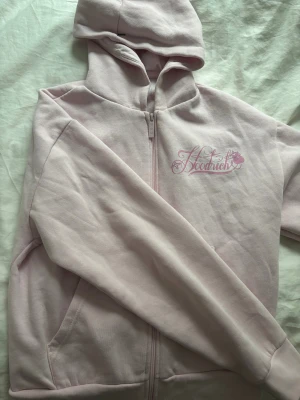 Ljusrosa hoodie från Hoodrich XS - Säljer en ljusrosa hoodie från Hoodrich i storlek XS. Tröjan har dragkedja framtill, huva och snyggt broderat Hoodrich-tryck i rosa på både bröstet och ryggen. Mjuk bomullskvalitet och klassisk passform med långa ärmar och fickor på sidorna. Nypris 880