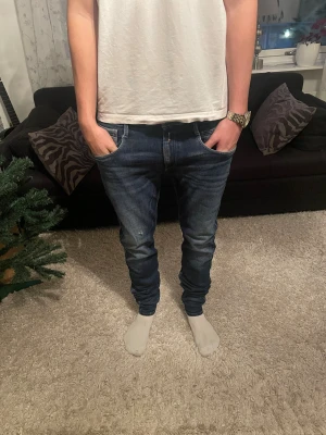 Blå jeans från Replay herr - Säljer ett par snygga blå jeans från Replay med klassisk femficksdesign och raka ben. Jeansen har normal passform och är tillverkade i slitstarkt denimtyg. Perfekta för dig som gillar mörka jeans, men även bra för vintern! W32 L34