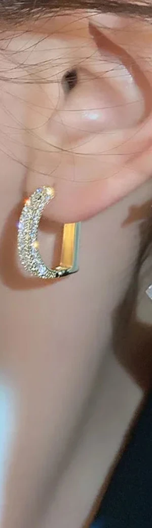 D örhängen i guld med strass - Säljer ett par lyxiga D örhängen i guldtonad metall, formade som ett D och dekorerade med glittrande strass. De har en chunky design och ger riktigt snygg bling-effekt. Perfekta för dig som vill sticka ut med exklusiva detaljer.