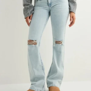 Nelly ljusblå bootcut jeans med broderi - Snygga ljusblå jeans från nelly med bootcut passform och slitna detaljer vid knäna. Jeansen har rosa broderi på bakfickorna och klassisk femficksdesign och med lågmidja. säljer då de inte kommer till användning! pris kan diskuteras❣️