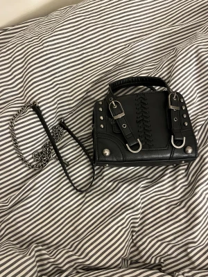 Svart väska från Zara - Cool svart axelväska från Zara med snygga silver detaljer. Axel bandet går även att ta av.