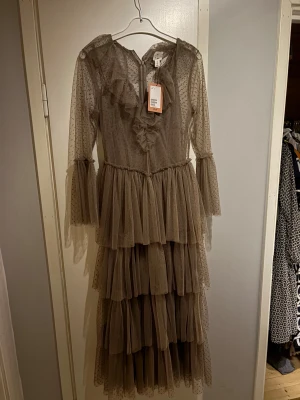 Beige Sandra mansour klänning - Säljer en beige långklänning från Sandra mansour, helt ny med prislapp