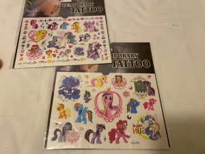 My Little Pony temporära tatueringar - Tre ark med färgglada temporära tatueringar med My Little Pony-motiv. Varje ark har olika ponnyfigurer i rosa, lila, blå, gul och orange, med detaljer som stjärnor, hjärtan och regnbågar. Perfekt för att skapa en lekfull look med söta och fantasifulla motiv. 50kr/2st/bild 