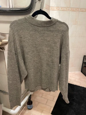 Grå stickad tröja med rund hals - En enkel och snygg grå stickad tröja med rundad hals och långa ärmar. Tröjan har en loose passform 