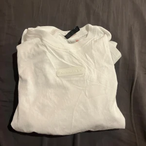 Vit Formula 1 t-shirt med tryck - Vit t-shirt från Formula 1 med stilren logotyp framtill och stort svartvitt tryck på ryggen med texten 'Who says life isn't a race?' och motiv av racerbilar. Klassisk passform och rund hals. Perfekt för dig som älskar motorsport och vill ha en clean look.