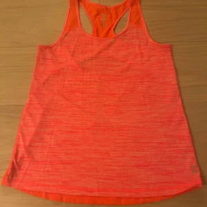 Neonrosa träningstopp från SOC XS - Säljer en neonrosa linnetopp från SOC i storlek XS. Toppen har brottarrygg, meshdetaljer och reflekterande rand på ryggen. Tillverkad i lätt och ventilerande syntetmaterial, perfekt för träning. Snyggt mönstrad i olika rosa nyanser.