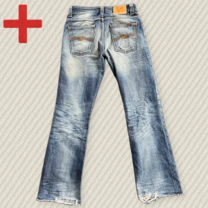 Bootcut Nudie Jeans  - Ett par riktigt snygga och trendiga Bootcut Nudie Jeans i storlek 29/32 (se mått nedan). Modellen heter Bootcut Ola. Har snygga fabriksslitningar vid knäväcken och på bakfickorna. Har heeldrag men jag antar att den var så från fabrik. Skriv om du har frågor!  Mått: Midja – 39 cm, Innersöm – 79 cm, Yttersöm – 102 cm, Lår – 27 cm, Benöppning – 22 cm.