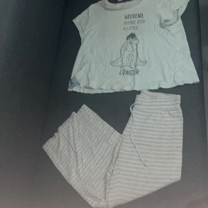 Pyjamas med Ior-tryck - Pyjamas T-shirt med korta ärmar + byxor och ett gulligt Ior-tryck från Nalle Puh på framsidan. Texten 'Weekend, please stay a little longer' ger en chill vibe. T-shirten har en avslappnad passform och är gjord i mjuk bomull, perfekt för att hänga hemma.