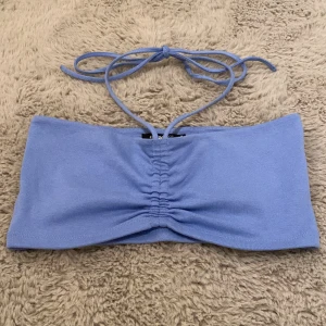 Ljusblå bandeau tubtopp Gina Tricot - Säljer en ljusblå bandeau tubtopp från Gina Tricot i storlek M. Toppen har snörning i nacken och snygg rynkning framtill. Mjuk och stretchig bomullskänsla, perfekt för varma dagar. Enkel och stilren design som är lätt att matcha. Aldrig använd, men saknar prislapp, köpt för ett halvår sedan, säljer då den ej kommer till användning. 