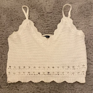 Vit stickad topp från Gina Tricot - Supersöt vit stickad topp från Gina Tricot i storlek M. Toppen har smala axelband, v-ringad hals och fina virkade detaljer med hålmönster och vågig kant nedtill. Använd en gång, säljer då den är för stor för mig. 