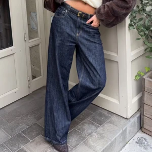 Buckle baggy jeans - Snygga mörkblå jeans med breda ben. Modellen har låg midja och ett coolt bältesband bak. Klassisk femficksdesign. Helt oanvända! Finns en matchande jeansjacka ute för försäljning i min profil!