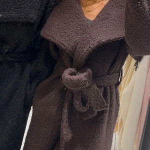 Brun teddyjacka med bälte - Säljer en brun teddyjacka med bred krage och knytbälte i midjan. Jackan har en oversized passform och är gjord i mjukt teddy-material som ger en mysig vibe. Perfekt för att hålla sig varm och se chill ut under höst och vinter.