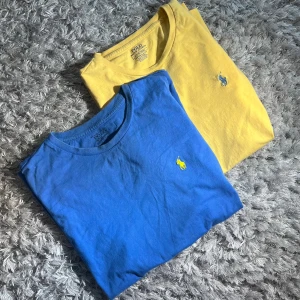 2 st Ralph Lauren T - shirts, crewneck  - 2 st snygga Raffe T - shirts i toppskick säljes! Tröjorna är båda två 100 % bomull och har inga defekter. Skick 9/10. Blå är herrstorlek - M och gul - S. Blå har AB - 50 och L - 60, Gul har AB - 40 och L - 68. Skriv för mer info eller bilder!🤝👏       
