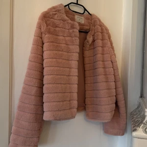 Rosa pälsjacka från Cream - Säljer en fluffig och mjuk rosa pälsjacka från Cream i storlek 36. Jackan har horisontella ränder, rund hals och är helfodrad. Perfekt för dig som vill ha en cozy och stylish look med lite extra attityd. Långärmad och riktigt skön att bära.