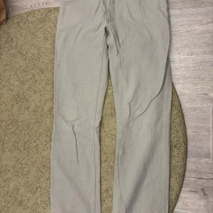 Beige byxor från Redwood Sportwear - Snygga beige byxor från Redwood Sportwear med klassisk femficksdesign och silverfärgad knapp med logga. Materialet är slitstarkt och har en lätt struktur, perfekt för dig som gillar stilrena och neutrala plagg. Passar dig som vill ha en enkel och clean look. w- 34 L-36 (tvättas innan postning)