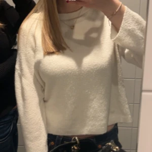 Vit stickad tröja - Mysig vit stickad tröja med croppad passform och rund hals. Tröjan har långa ärmar och är perfekt för dig som gillar en enkel och clean stil. Materialet är mjukt och ger en skön känsla mot huden. Passar dig som vill ha en basic men snygg tröja.