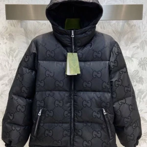 Svart pufferjacka från Gucci - Säljer en svart pufferjacka från Gucci med ikoniska GG-mönstret över hela jackan. Jackan har huva, två fickor med dragkedja och en rejäl dragkedja framtill. Perfekt för dig som vill ha en lyxig och varm jacka med streetkänsla.