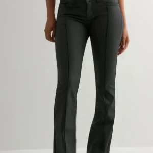 Svarta bootcut byxor med pressveck - Snygga svarta byxor från Nelly med bootcut och markerade pressveck framtill. Byxorna har två knappar i midjan, klassiska fickor och är tillverkade i ett mjukt bomullsmaterial med lite stretch. Perfekt för dig som gillar en stilren och trendig look. Prislappar bifogare!