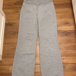 Grå mjukisbyxor från lager 157 - Säljer ett par grå mjukisbyxor med snörning i midjan. Byxorna har en rak och loose passform med breda ben och är tillverkade i mjukt bomullsmaterial. Perfekta för chill dagar eller när du vill vara extra bekväm.