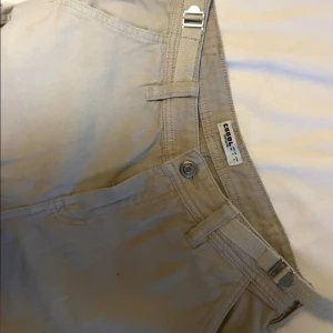 Ljus gråa cargobyxor - Snygga ljusgråa cargobyxor med praktiska fickor på benen och justerbara spännen i midjan. Använd några fåtal gånger