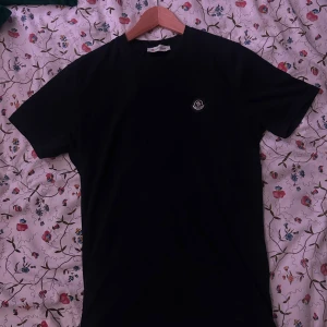 Svart Moncler t-shirt i bomull - Svart t-shirt från Moncler i mjuk bomull med klassisk passform. T-shirten har rund halsringning och Moncler-logga på bröstet. Enkel och stilren design som passar perfekt till jeans eller shorts. Nästan helt ny och jätte skön passform!