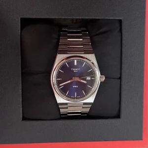 Tissot PRX klocka med blå urtavla (35mm) - Snygg Tissot PRX klocka med blå urtavla och datumvisning. Klockan har ett stilrent, borstat armband i silverfärgat stål och klassisk rund boett. Perfekt accessoar för dig som gillar tidlös och modern design. Levereras med originalask och tillbehör.