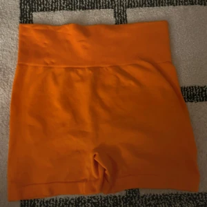 Orangea Träningsshorts  - Orangea (mer orangea än vad dom ser ut på bilderna) träningshorts i strl M med scrunch baktill. Använda 2 ggr och är i mycket bra skick!