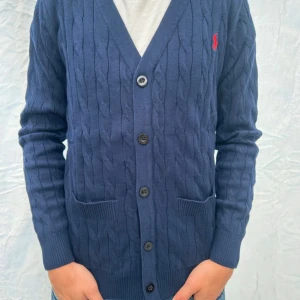 Ralph Lauren cardigan - Hej! Jag säljer nu denna riktigt snygga och stickade cardigan från Ralph Lauren i ett kabelstickat mönster. Den är i toppen skick och är aldrig använd, säljer då den är för stor för mig. Hör av er om ni har några frågor😃