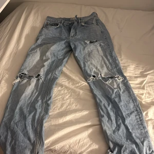Ljusa ripped jeans från g perfect - Snygga ljusblå jeans från g perfect jeans i storlek 36. Modellen har raka ben och flera slitningar både fram och bak för en cool, avslappnad vibe. Klassisk femficksdesign och knappstängning. Perfekta för dig som gillar streetstyle.